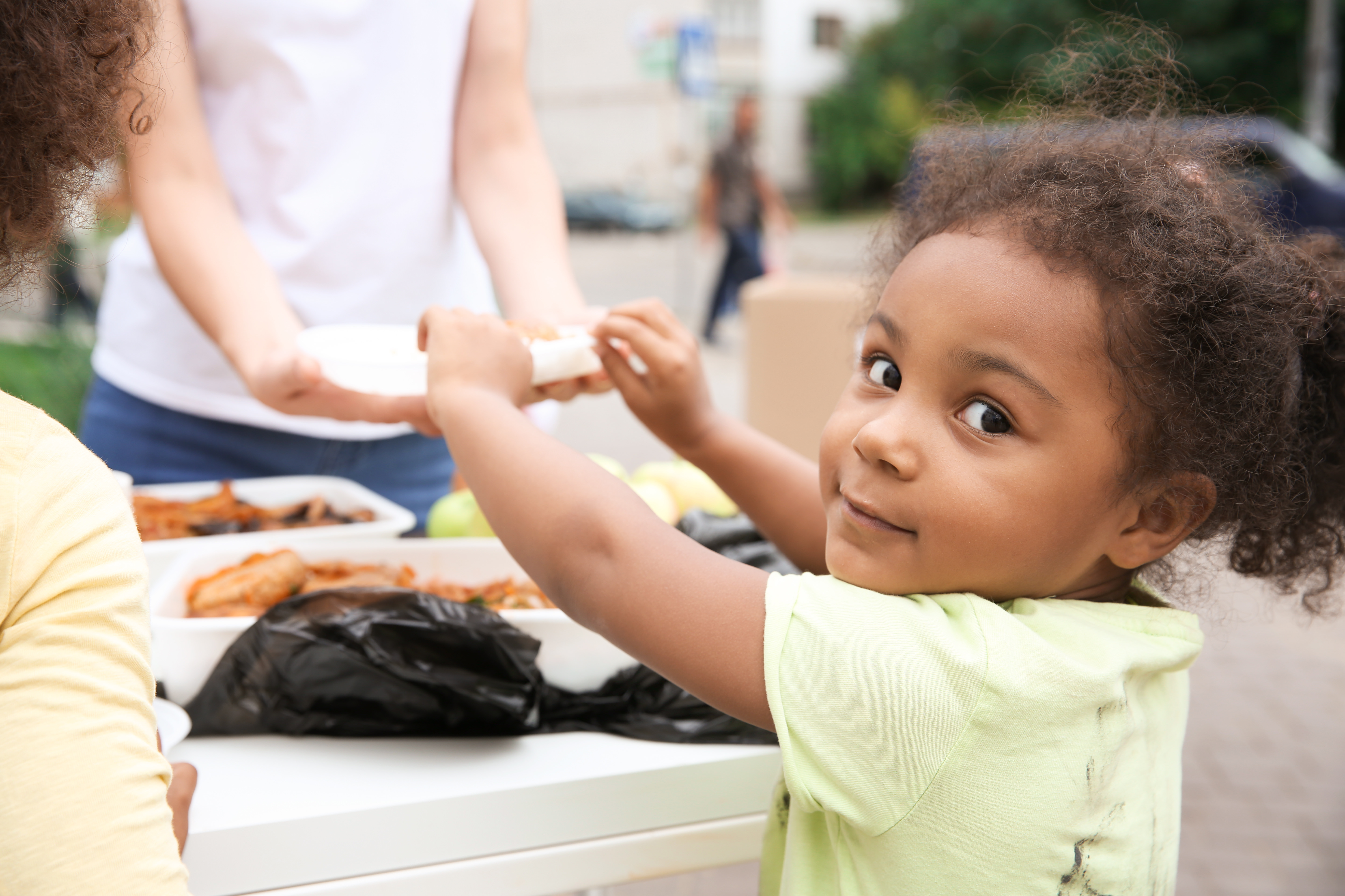 Volunteer sharing food with child outdoors